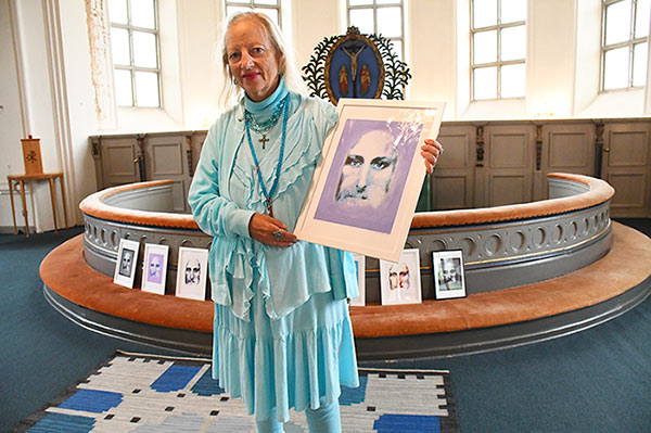 Ingela st&aring;r framme vid altaringen i Hamenda Kyrka och h&aring;ller en Lila Kristusbild